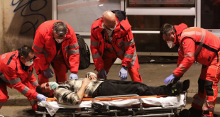 Un hombre con una máscara yace inconsciente en el suelo cerca de una para de autobús, el 22 de marzo en Roma, y es trasladado por las autoridades sanitarias